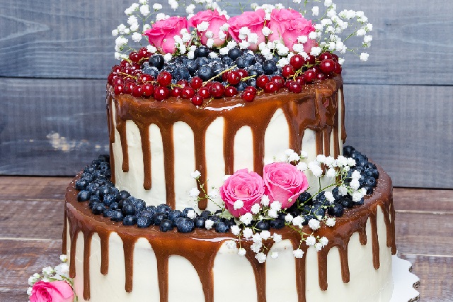 two layered color drip wedding cake with bilberries, red currants and roses
